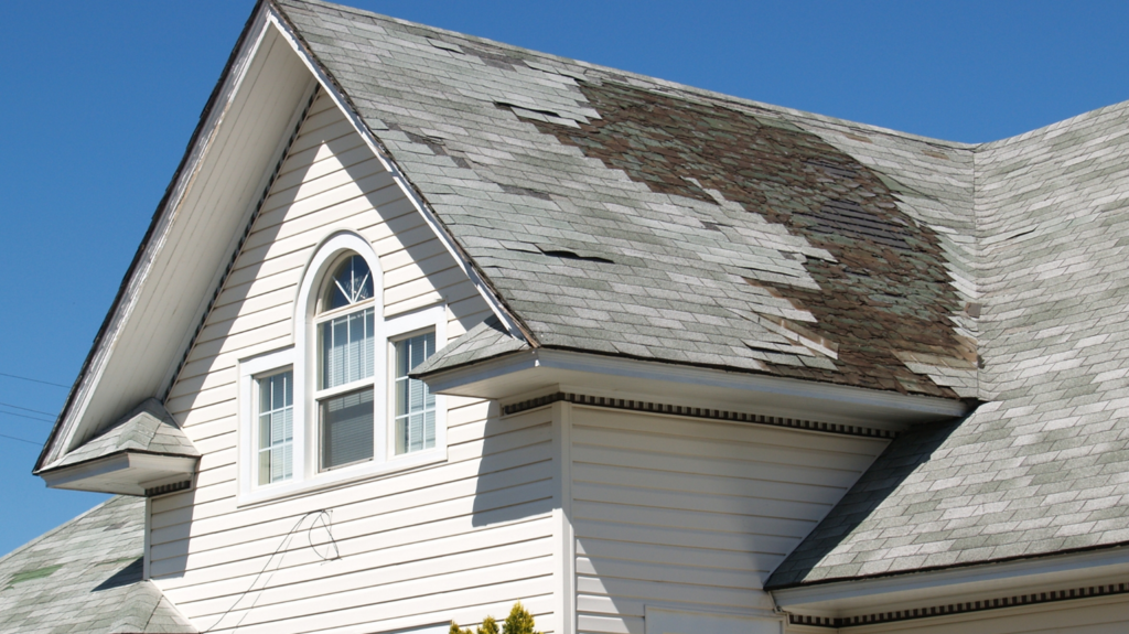 House with heavily damaged shingles requiring costly pre-listing roof repairs before selling.