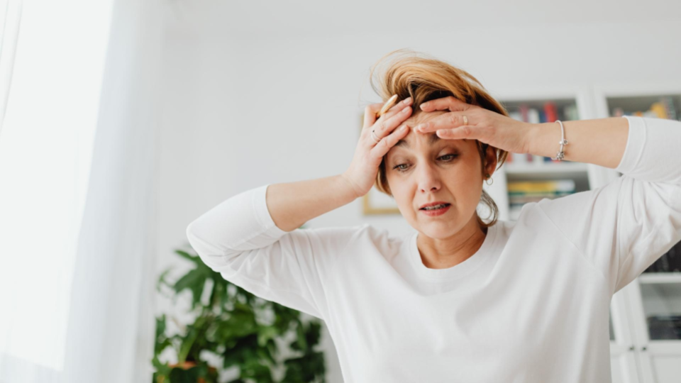 A woman holding her head in stress due to constant home showings and privacy concerns while selling a house.
